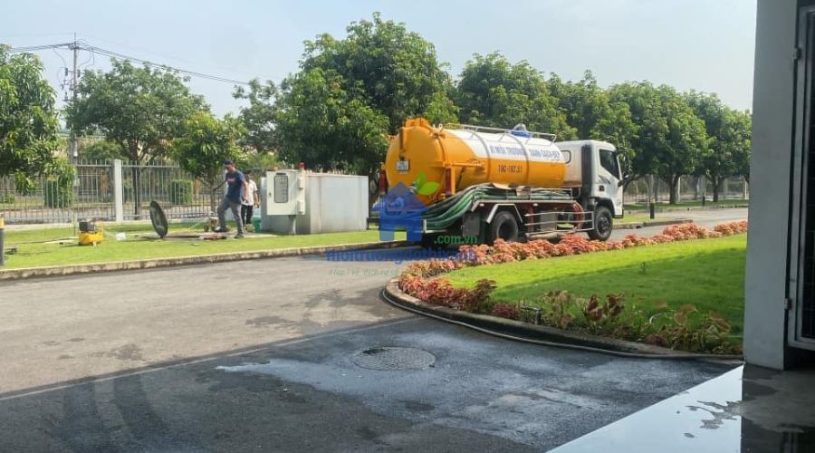 Xe hút bồn vàng đỗ bên đường, thợ đang thực hiện hút hầm cầu quận Tân Phú